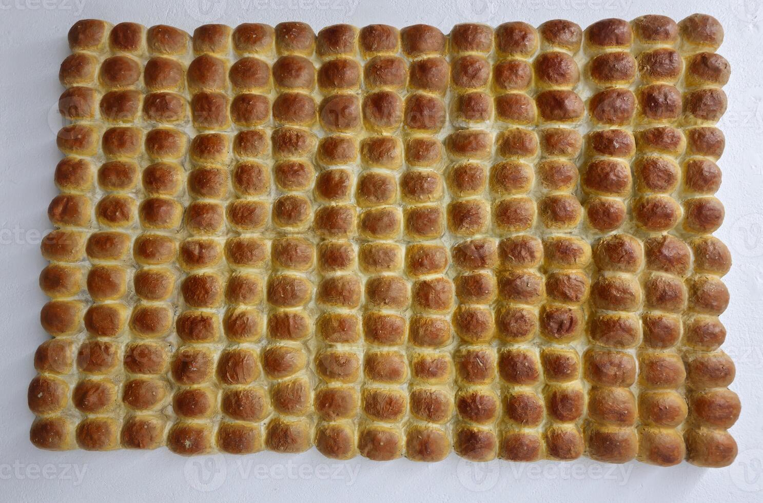 Pav is a soft, slightly sweet, square-shaped bread roll that is a staple in Indian cuisine Rows of bread-like or bun-like objects arranged neatly. They appear golden-brown, likely freshly baked. photo