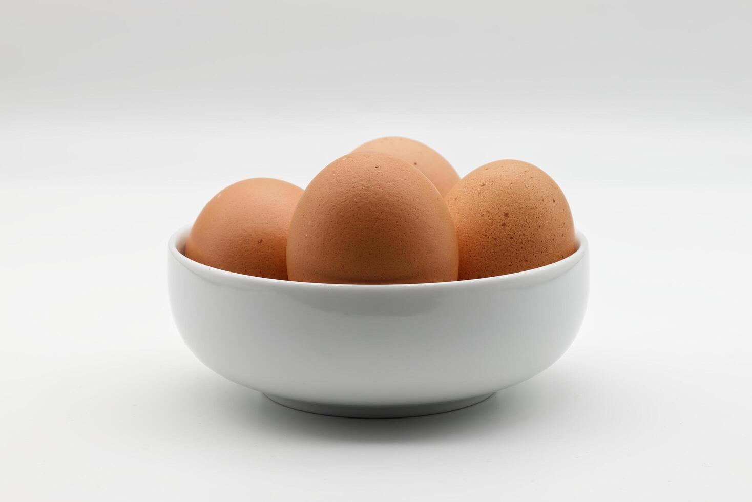 Fresh brown eggs in a white bowl isolated on white background photo