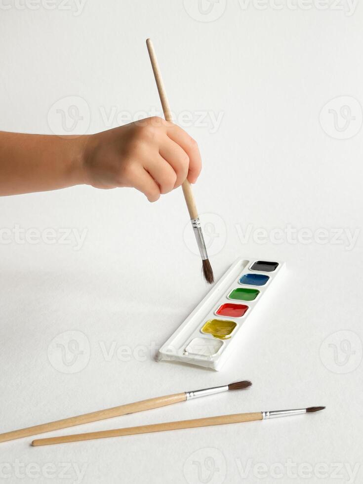 Childs hand painting with watercolors on white background photo