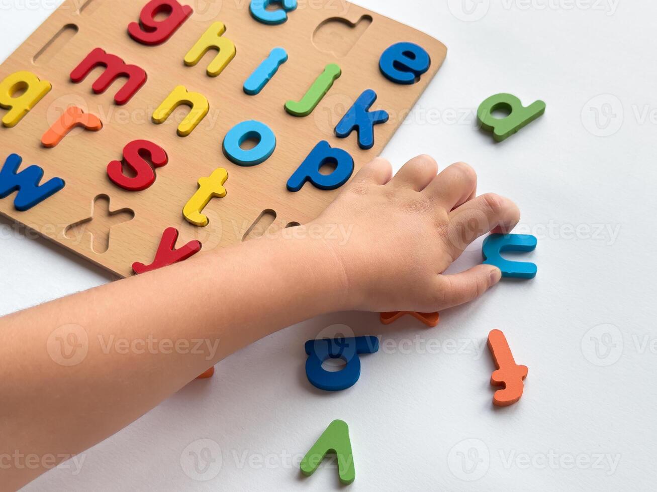 Child learning alphabet with colorful puzzle blocks on white background photo