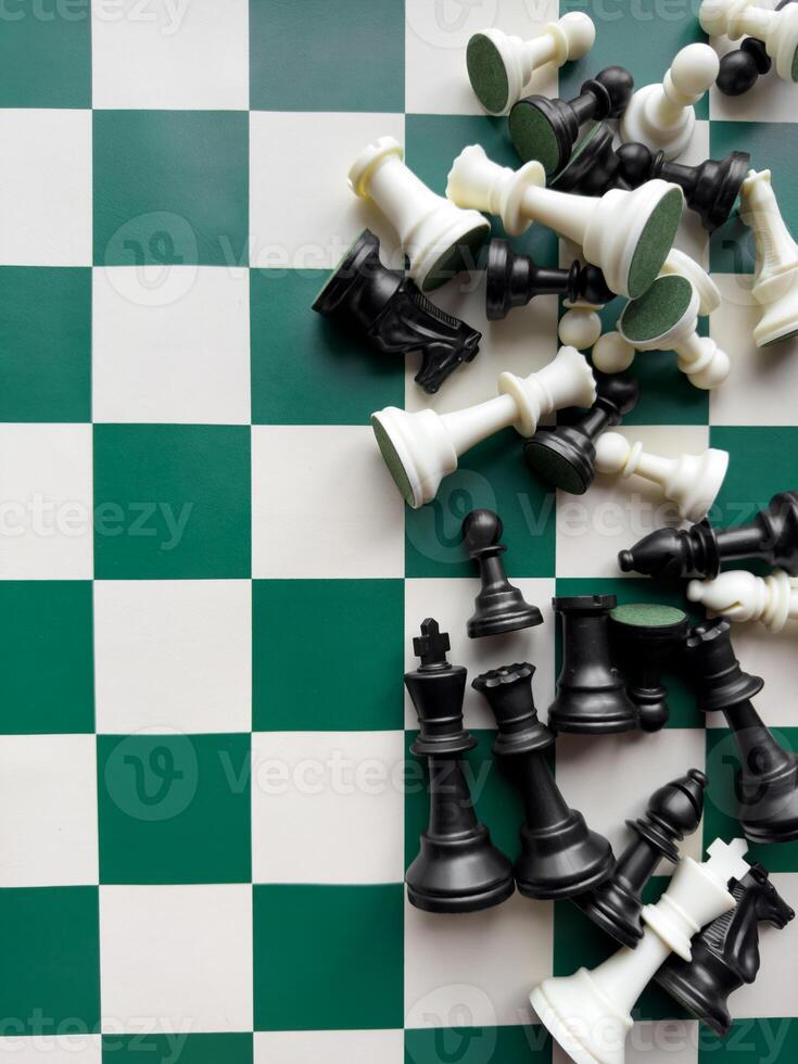 Scattered chess pieces on green and white board in a strategic match photo