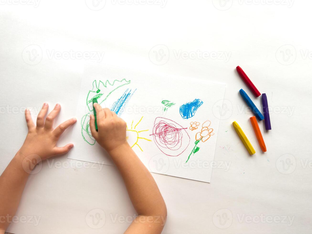 Child drawing colorful art with crayons on paper photo