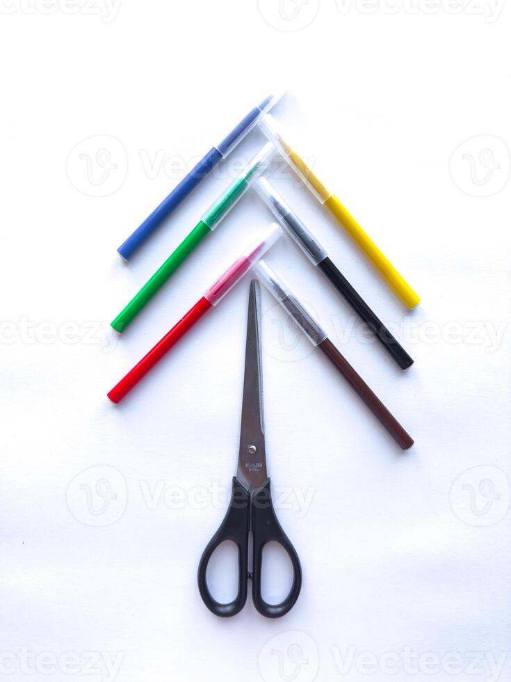 Colorful pens arranged around scissors in creative geometric pattern photo
