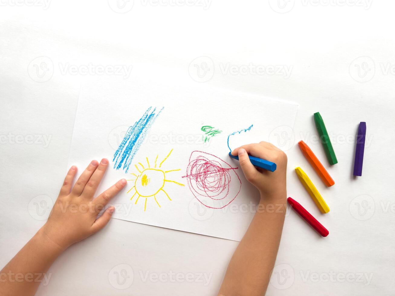 Childs hand drawing with colorful crayons on white paper. Creativity and imagination in action photo