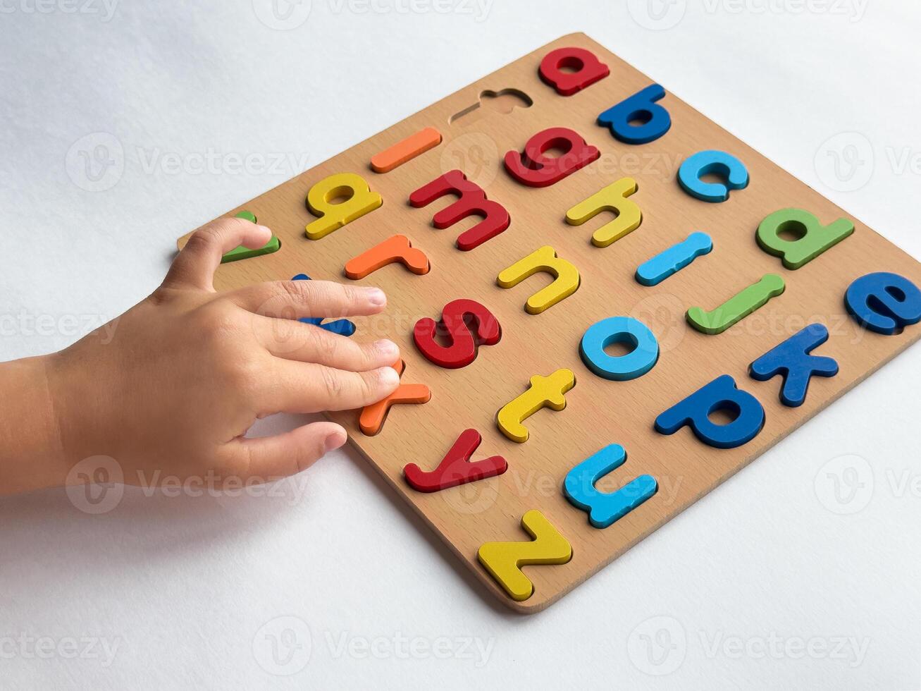 Child learning with colorful alphabet puzzle on white background photo