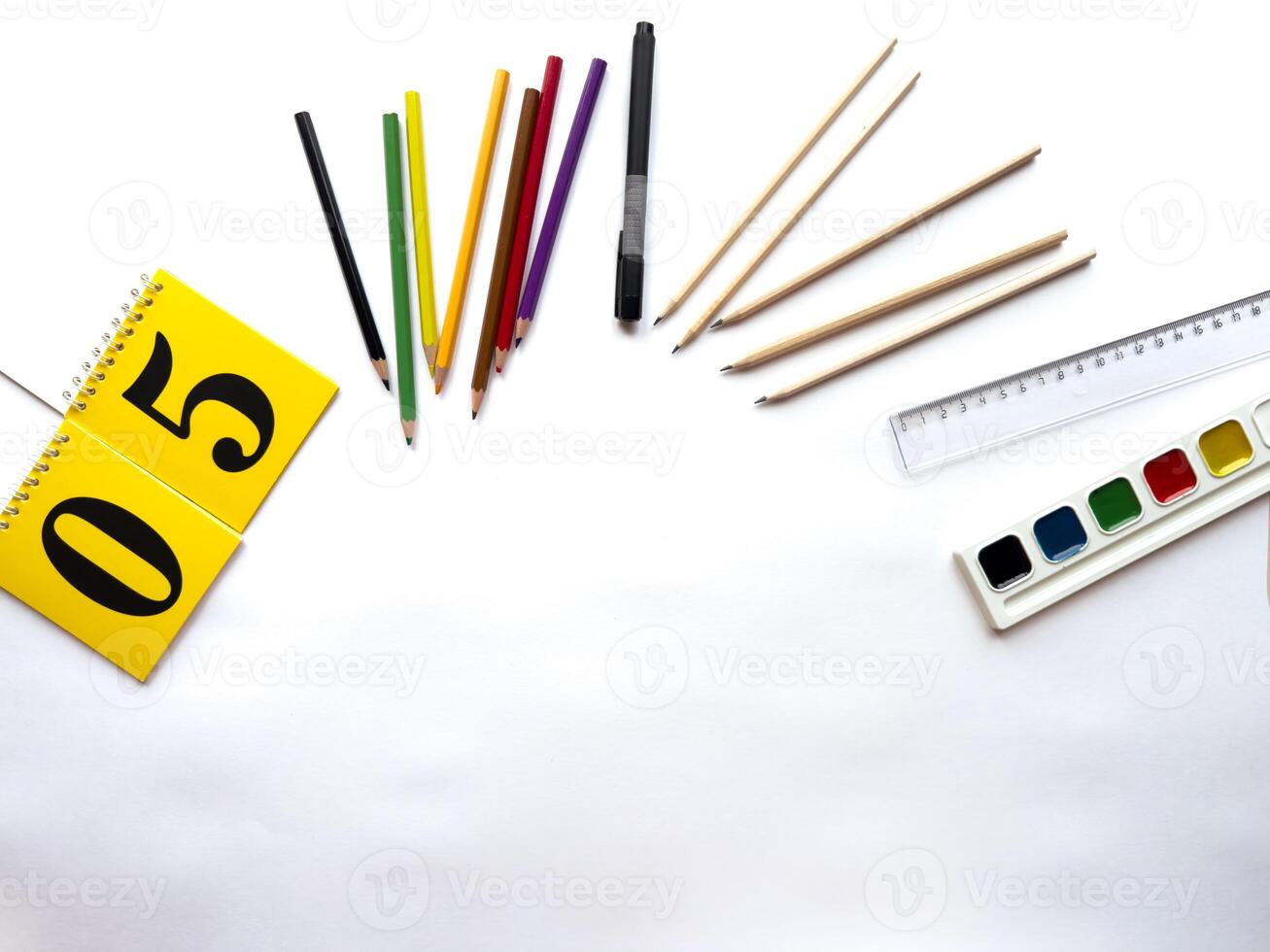 Creative workspace with color pencils, marker, notepad, and watercolors on white background photo