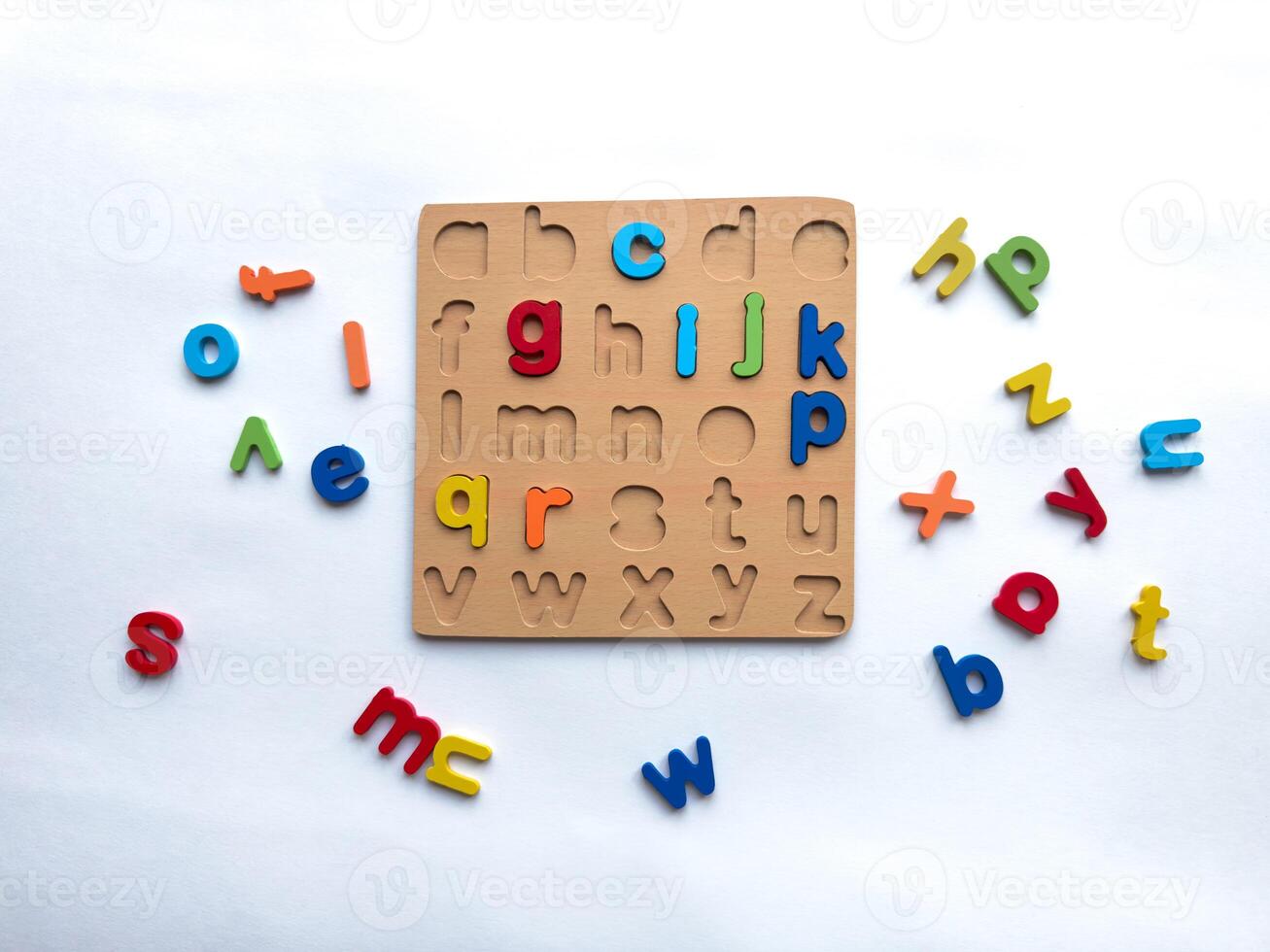 Colorful alphabet puzzle with wooden board and loose letters on white background photo
