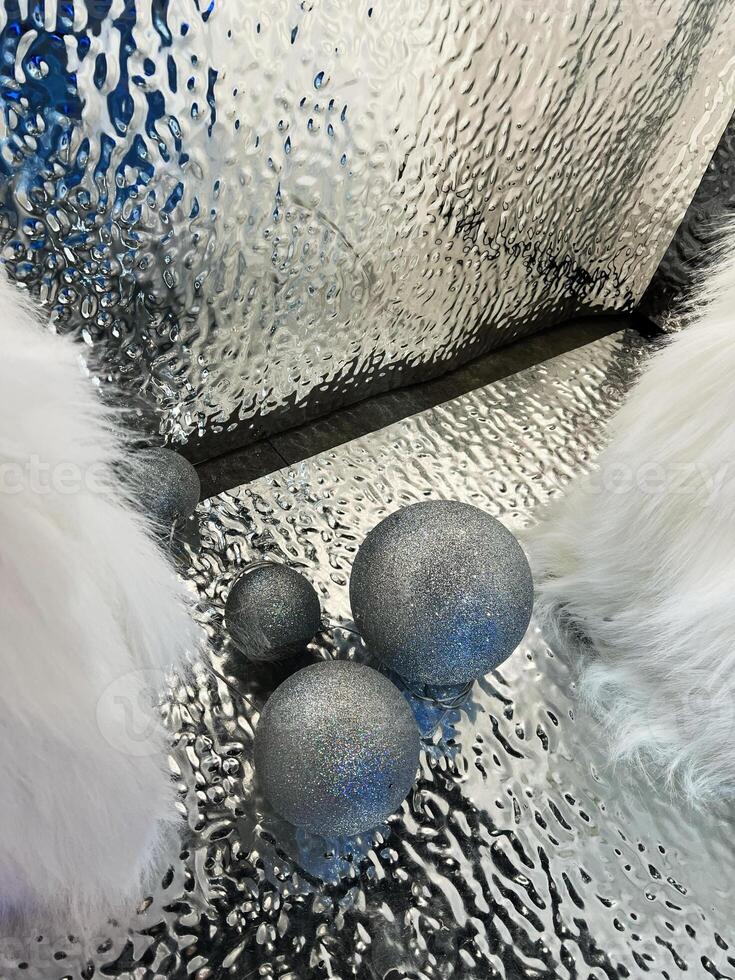 Silver glittering orbs on a textured reflective surface with fluffy white objects photo