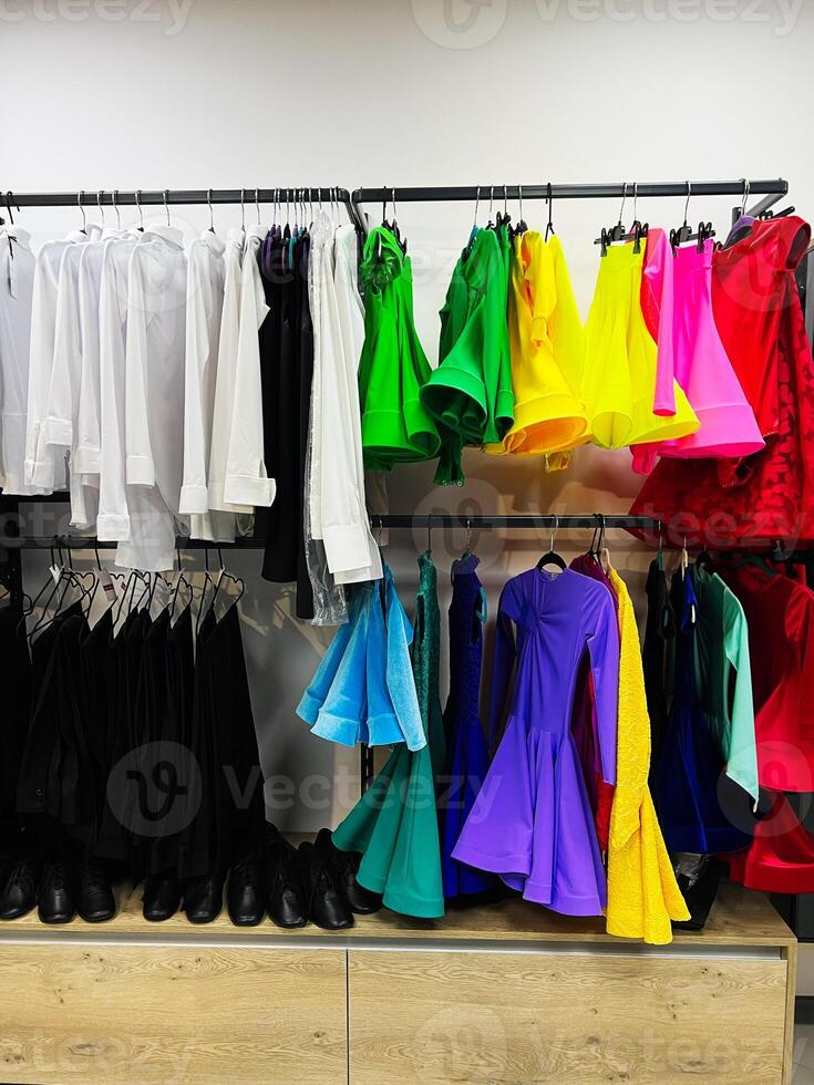 Colorful assortment of elegant dance dresses and formal clothing on display in a store photo