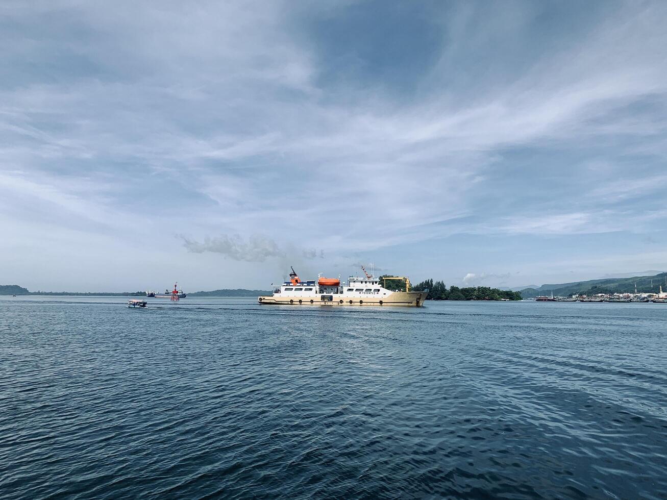 a ferry in the waters near a small island with a blue sky photo
