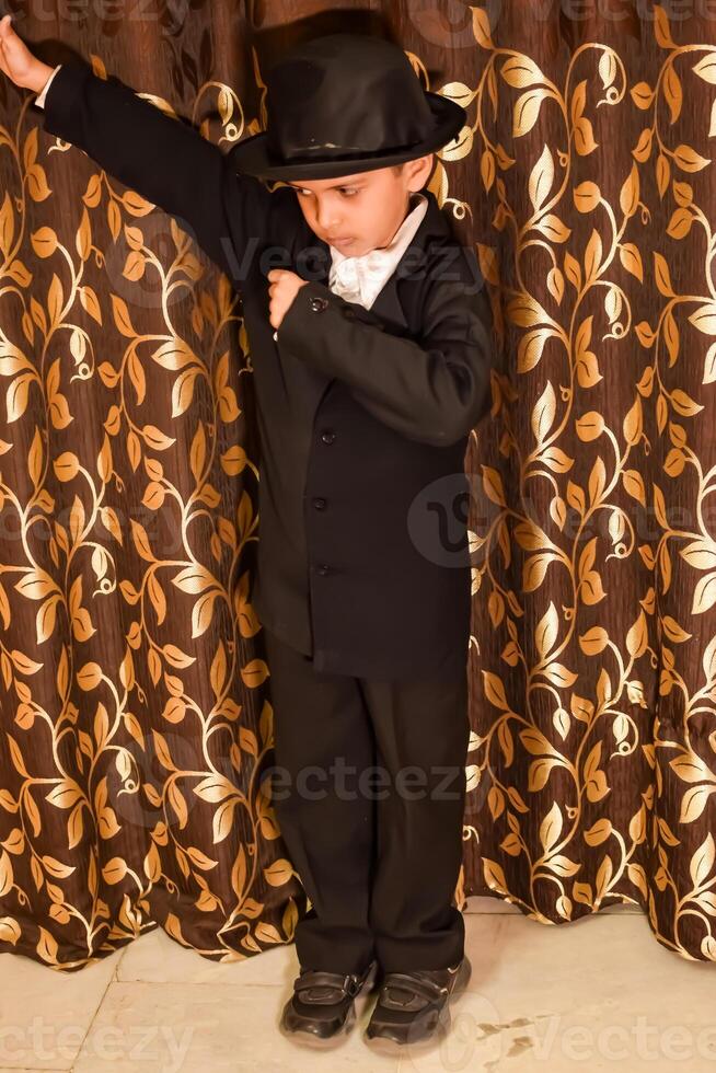 Cute Indian Boy posing with dance step, Asian child model shoot with black coat, pant and white shirt, Kid lifestyle concept shoot indoor photo