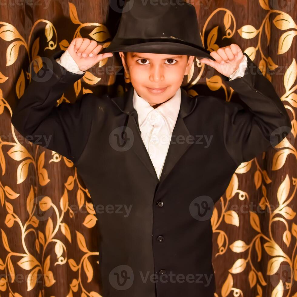 Cute Indian Boy posing with dance step, Asian child model shoot with black coat, pant and white shirt, Kid lifestyle concept shoot indoor photo