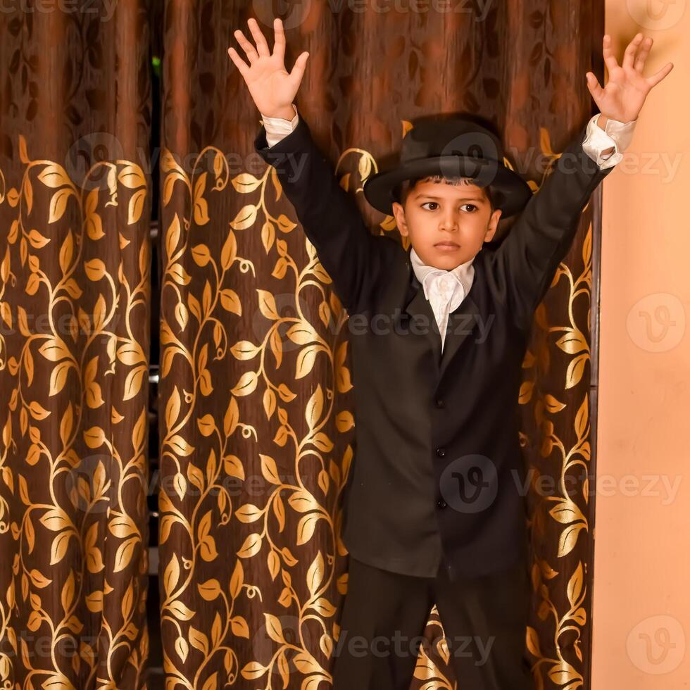 Cute Indian Boy posing with dance step, Asian child model shoot with black coat, pant and white shirt, Kid lifestyle concept shoot indoor photo
