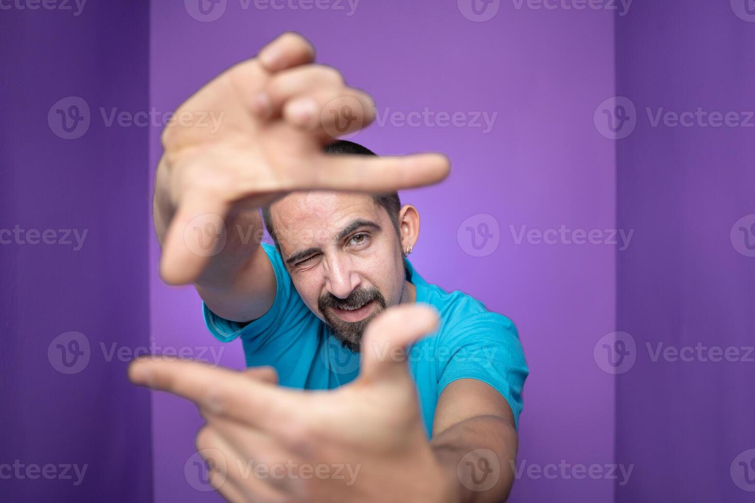 Young handsome man doing frame using hands palms and fingers, over purple background photo
