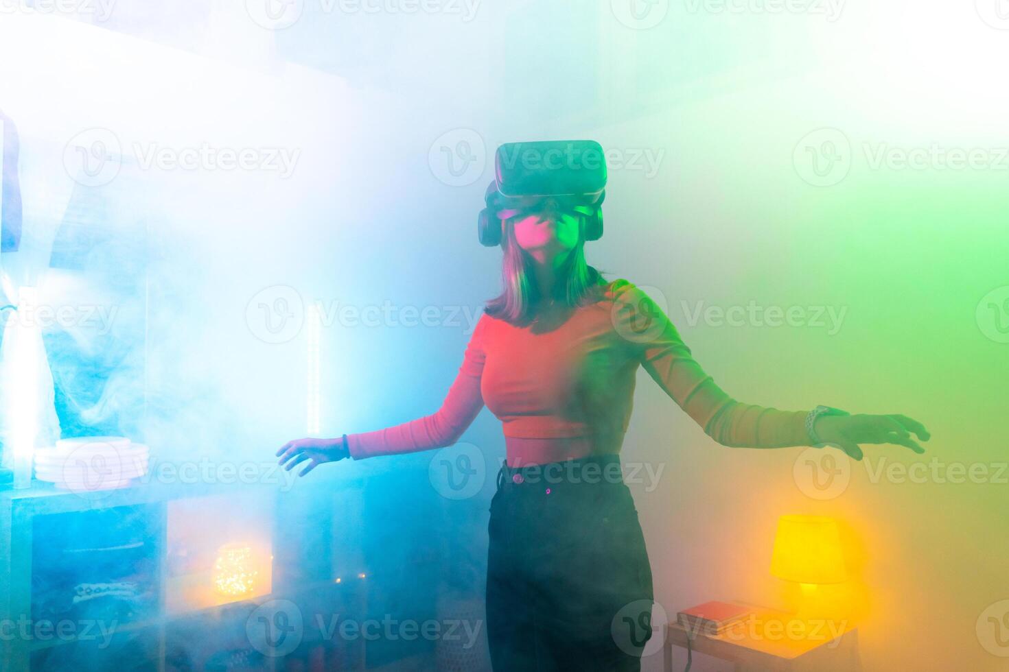 Young woman using virtual reality glasses in the dark room with neon lighting. Wireless technologies. photo