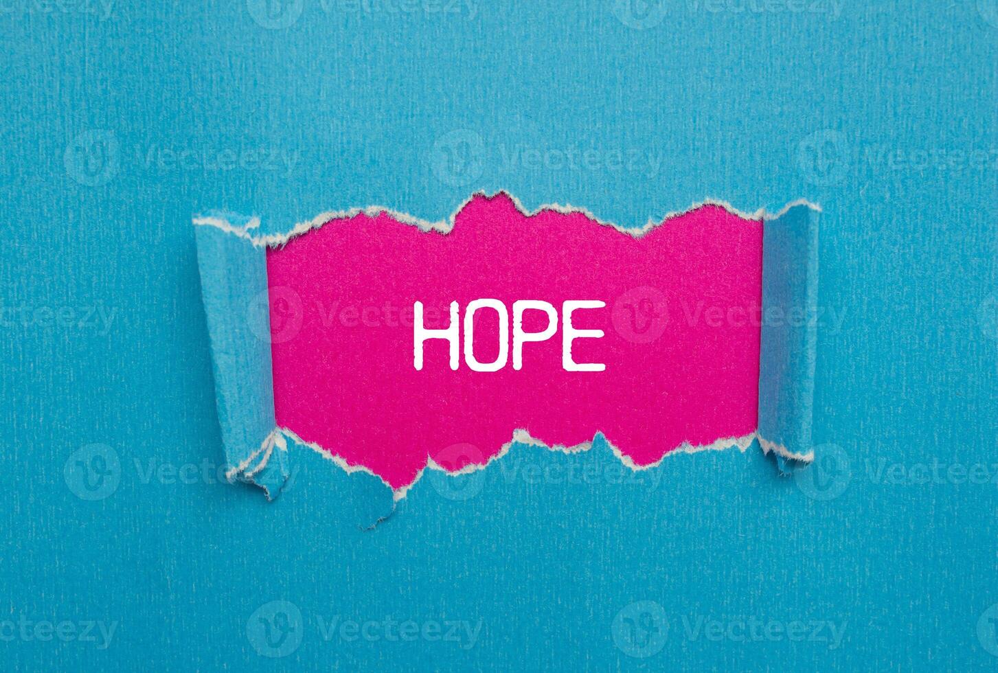 Hope message written on ripped torn blue paper with pink background. Conceptual hope symbol. Copy space. photo