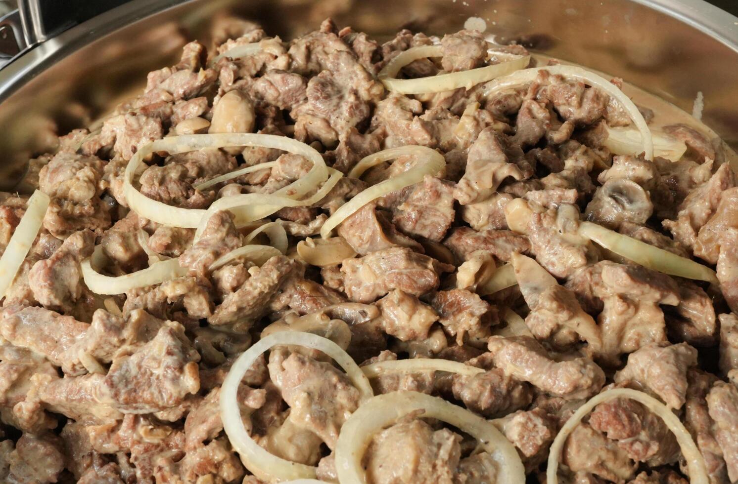 a pan with meat and onions in it photo