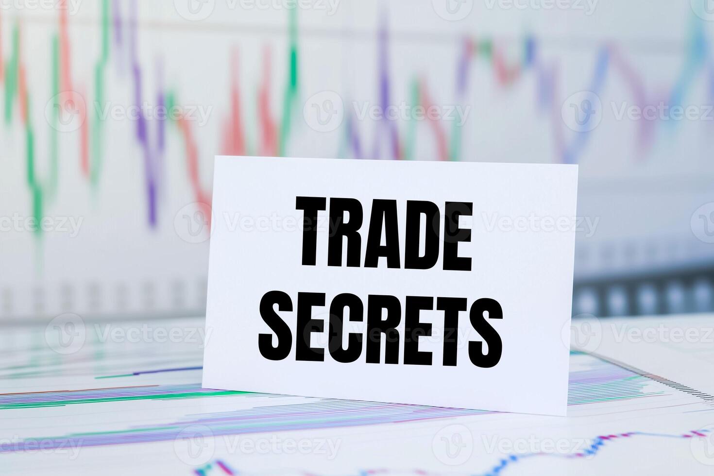 Trade secrets message written on white paper card with financial charts and documents. Conceptual trade secrets symbol. photo