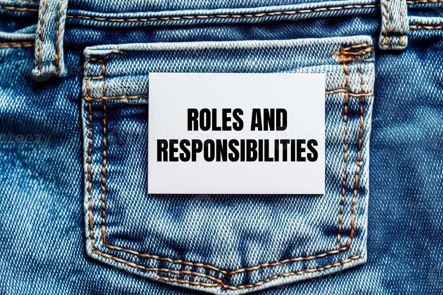 Roles and responsibilities message written on white card on denim jean background. Conceptual roles and responsibilities symbol. Copy space. photo