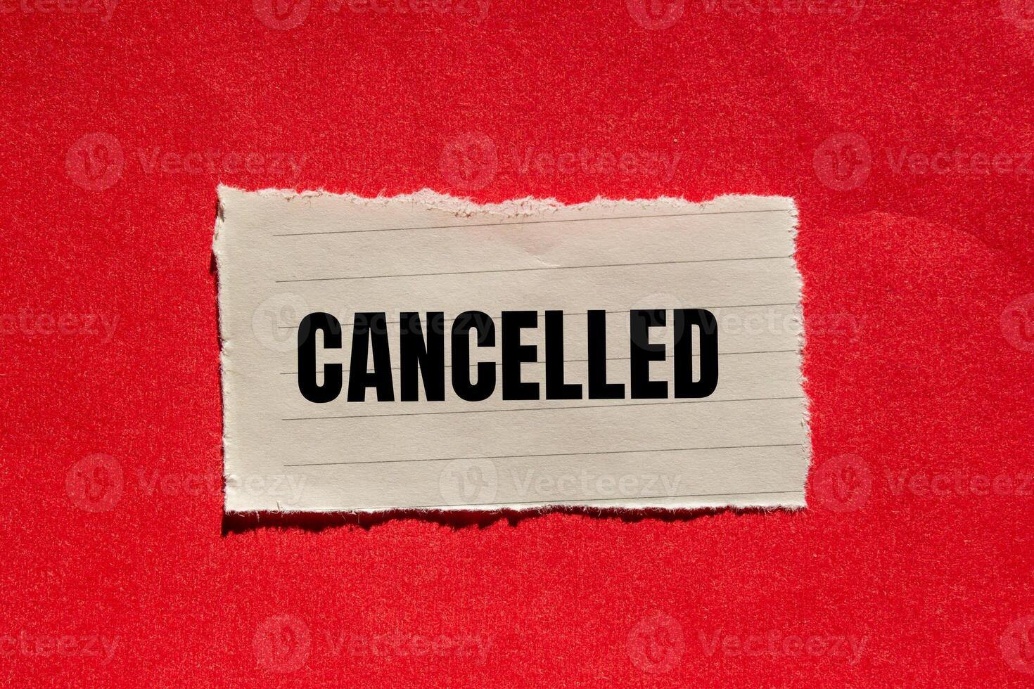 Cancelled message written on ripped torn paper piece with red background. Conceptual cancelled symbol. Copy space. photo