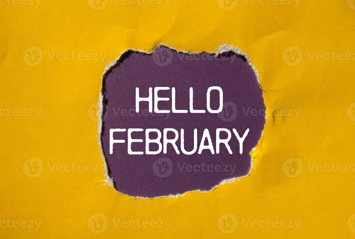 Hello february message written on ripped torn yellow paper with purple background. Conceptual hello february symbol. Copy space. photo