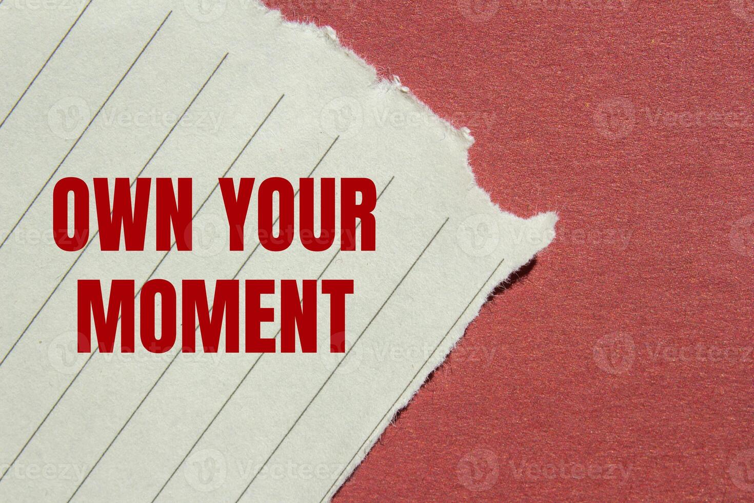 Own your moment message written on ripped torn lined paper with red background. Conceptual own your moment symbol. Copy space. photo
