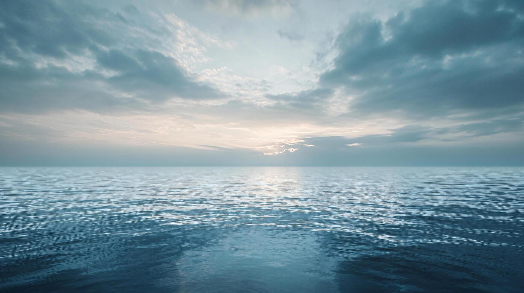 The ocean is calm and the sky is cloudy. The sun is setting, casting a warm glow over the water photo