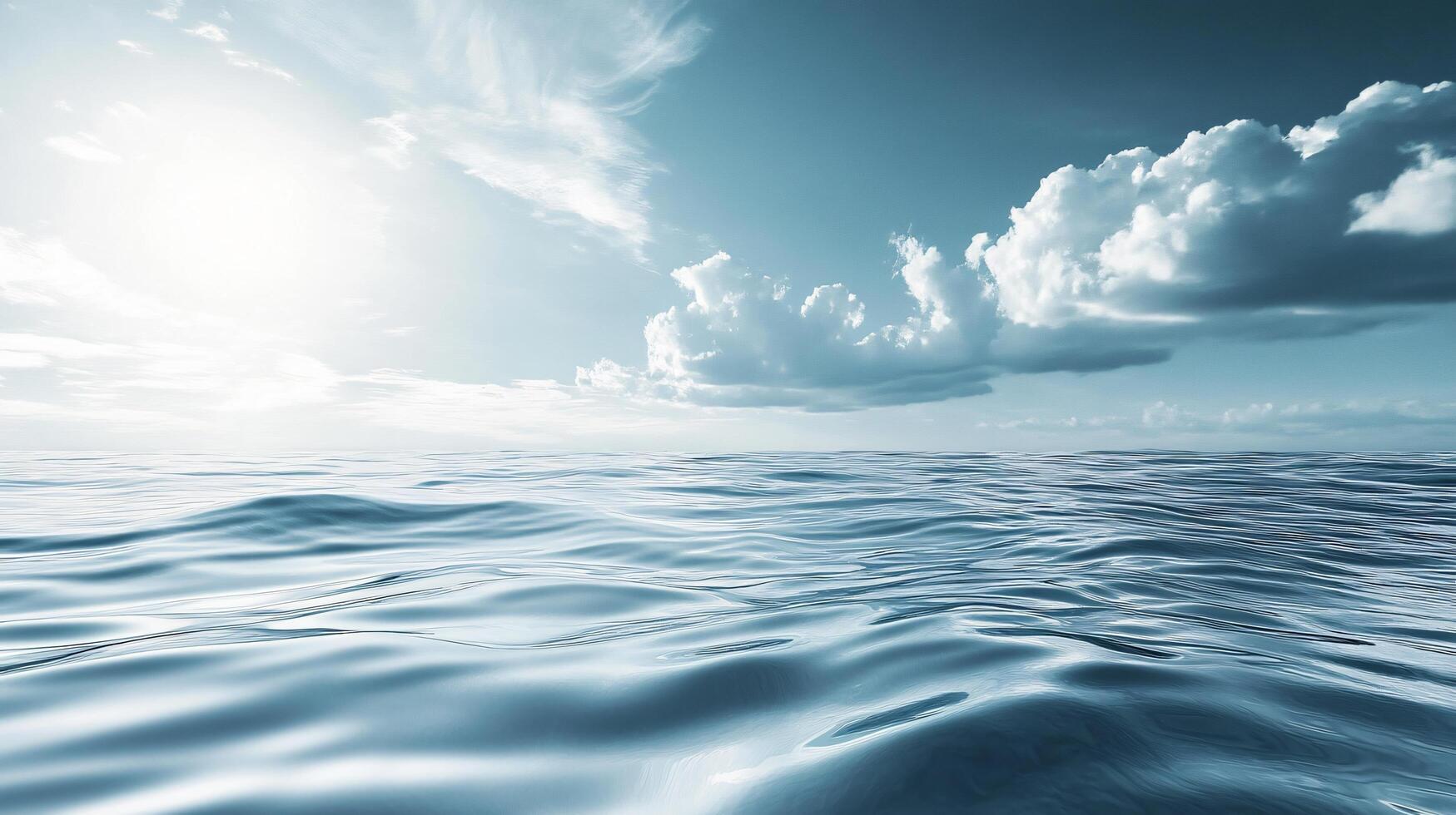 Calm ocean with a few clouds in the sky. The sky is blue and the sun is shining photo