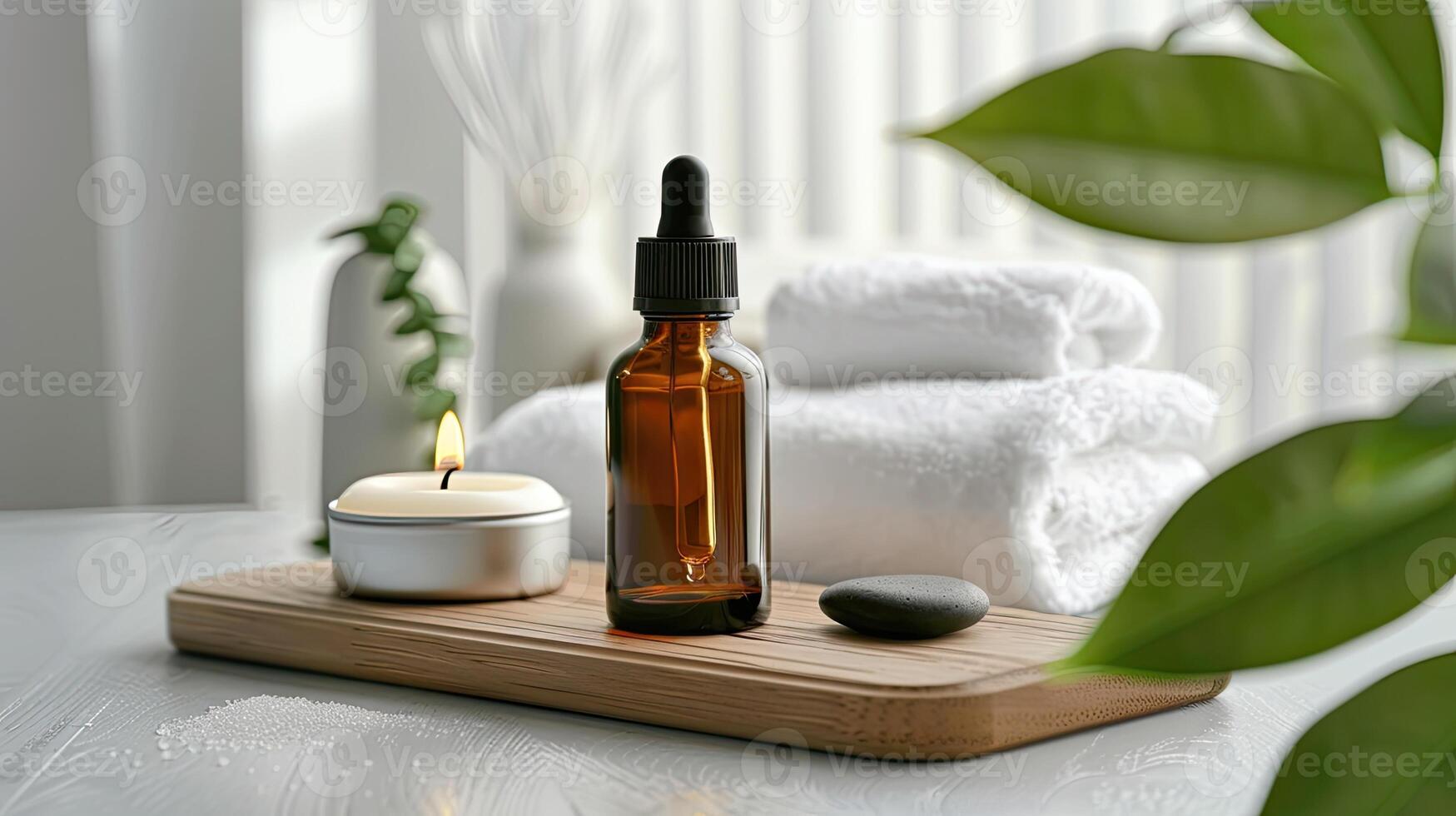 A bottle of essential oil sits on a tray next to a towel and a candle photo