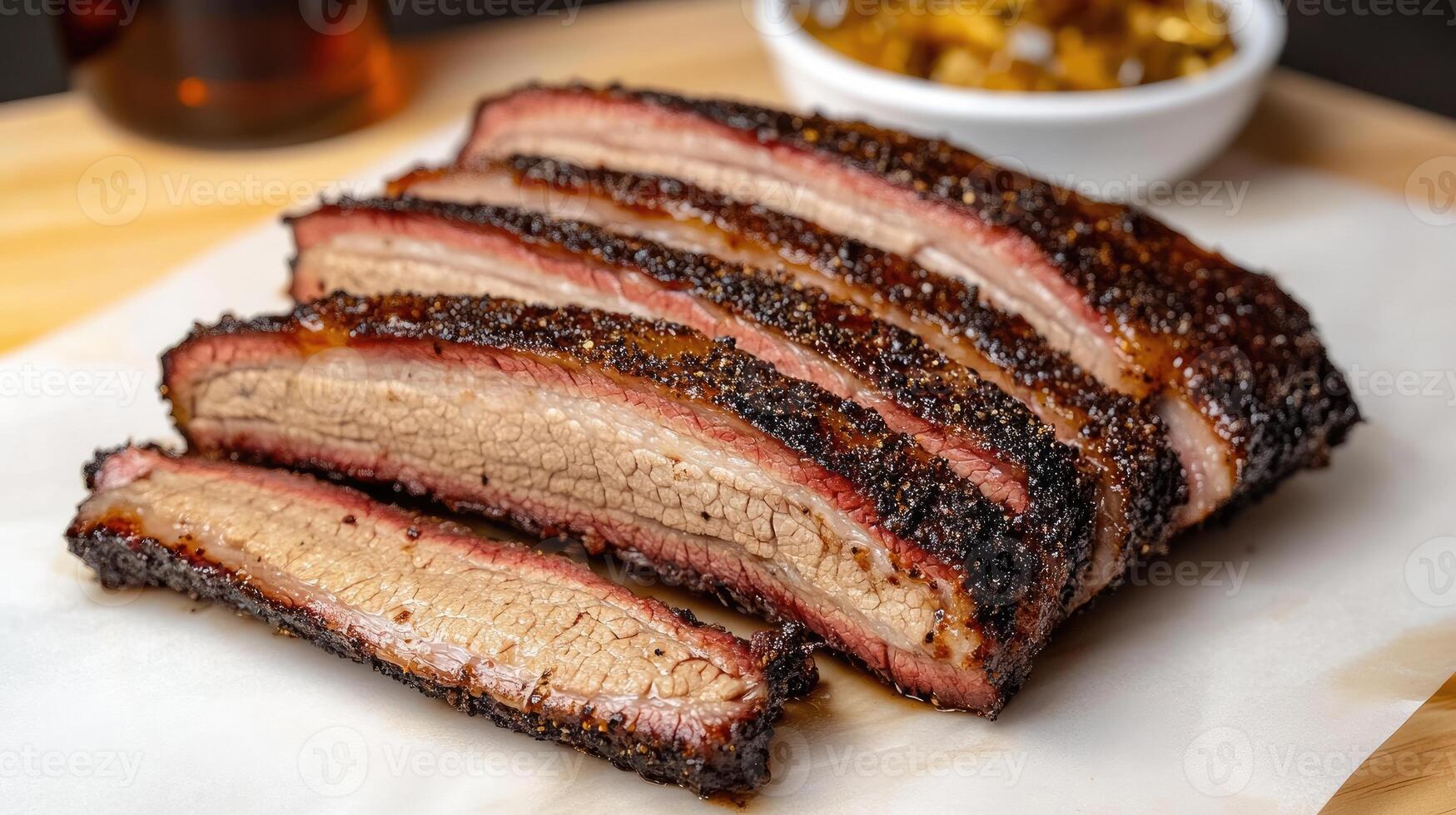 A sliced brisket on a cutting board with a side of sauce photo