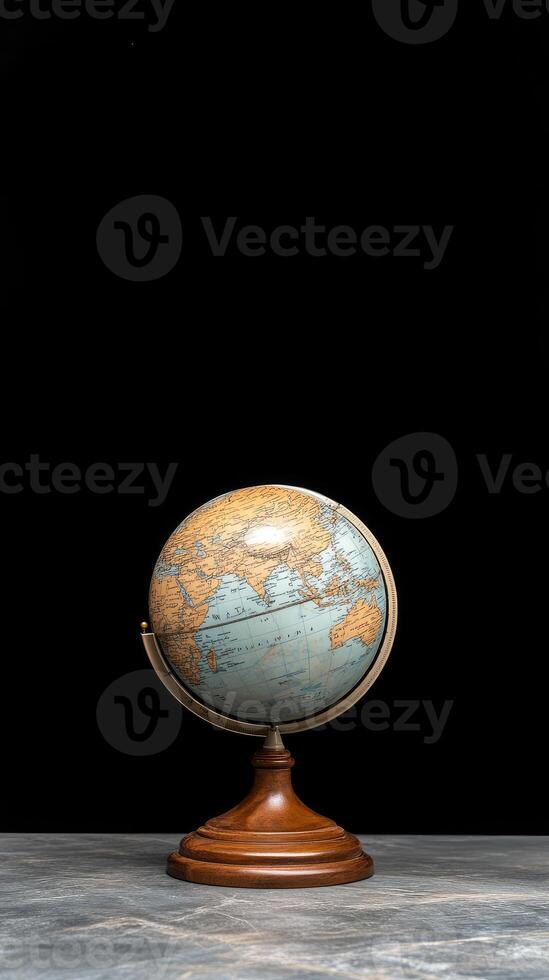 A small globe on a wooden stand in front of a black background photo