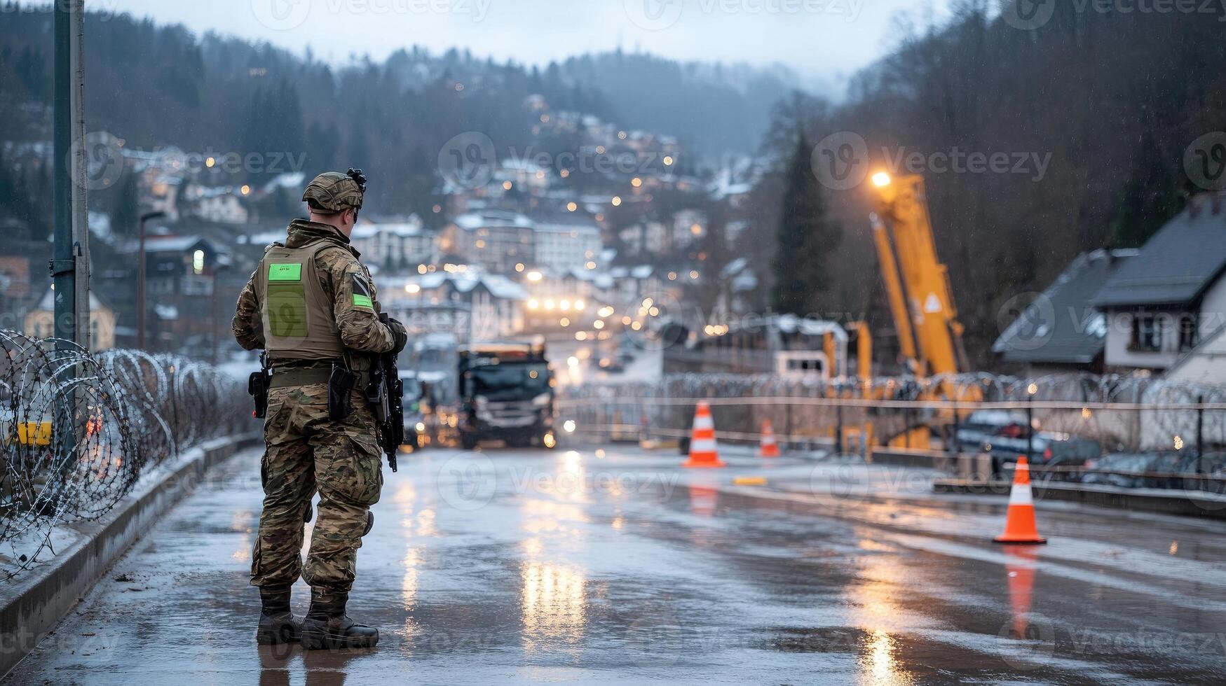 A soldier stands on the side of a road in the rain photo