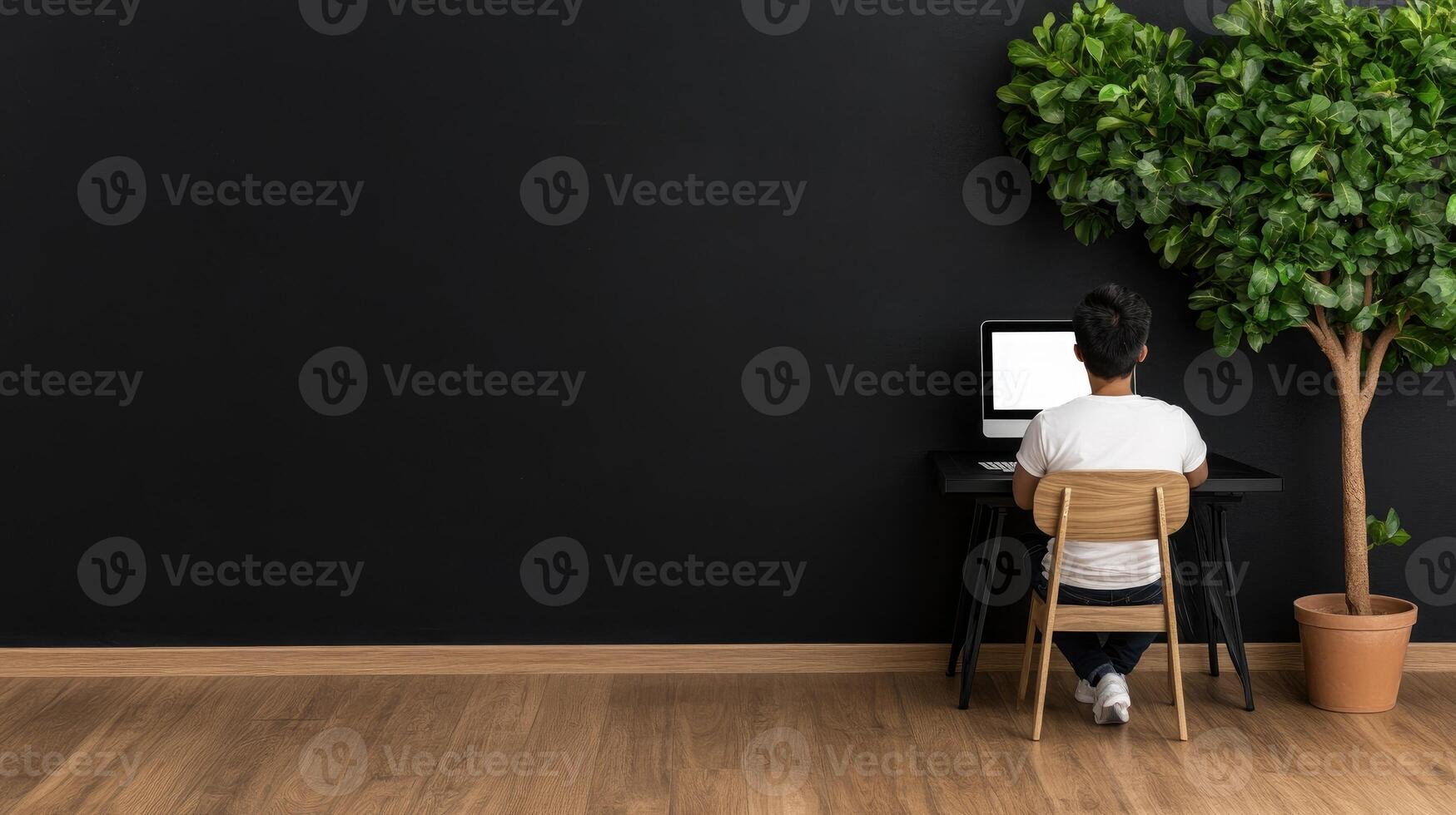 A person sitting at a desk with a computer and a tree photo