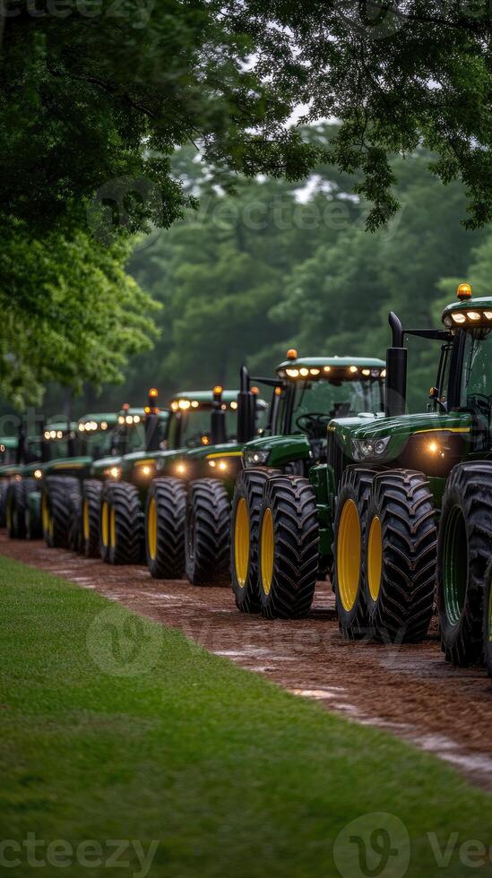 A row of green tractors parked on a dirt road photo