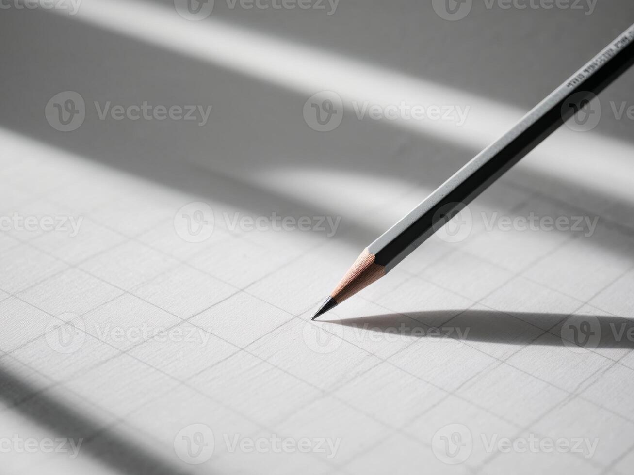 A pencil is on a piece of paper with a grid. photo