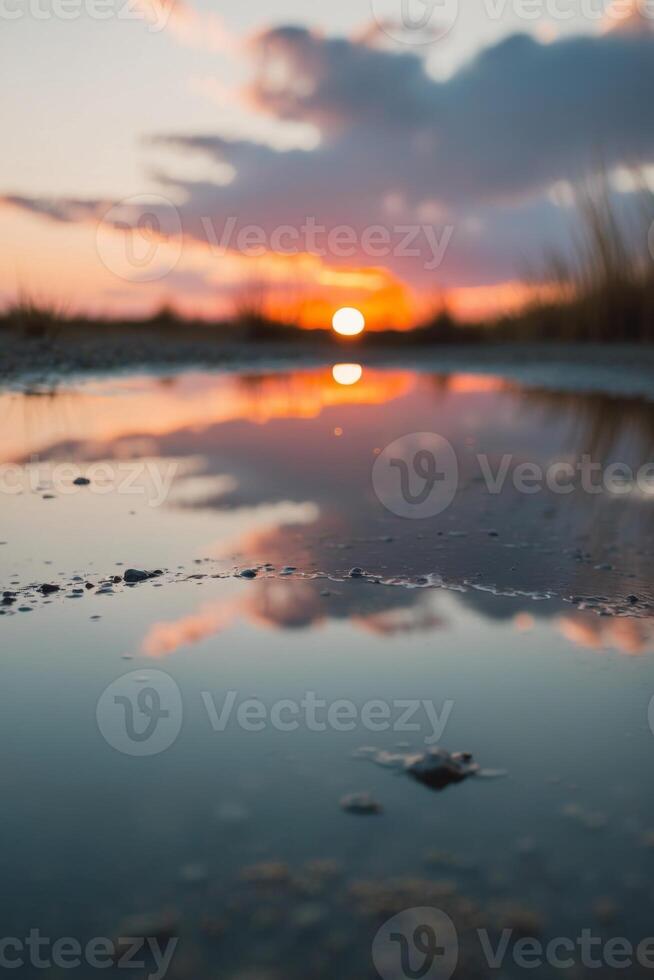 A puddle of water with the sun setting in the background. photo