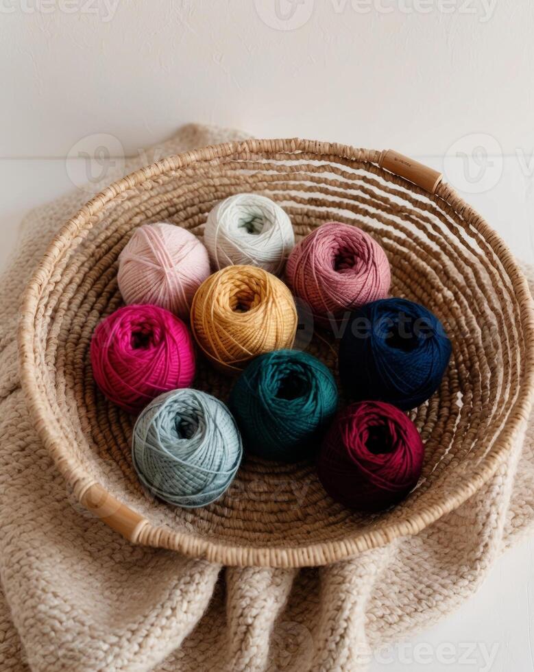 Variety of colorful yarn balls in a woven basket on a cozy knit blanket photo