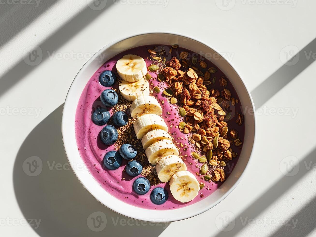 A bowl of blueberry smoothie with banana and granola photo