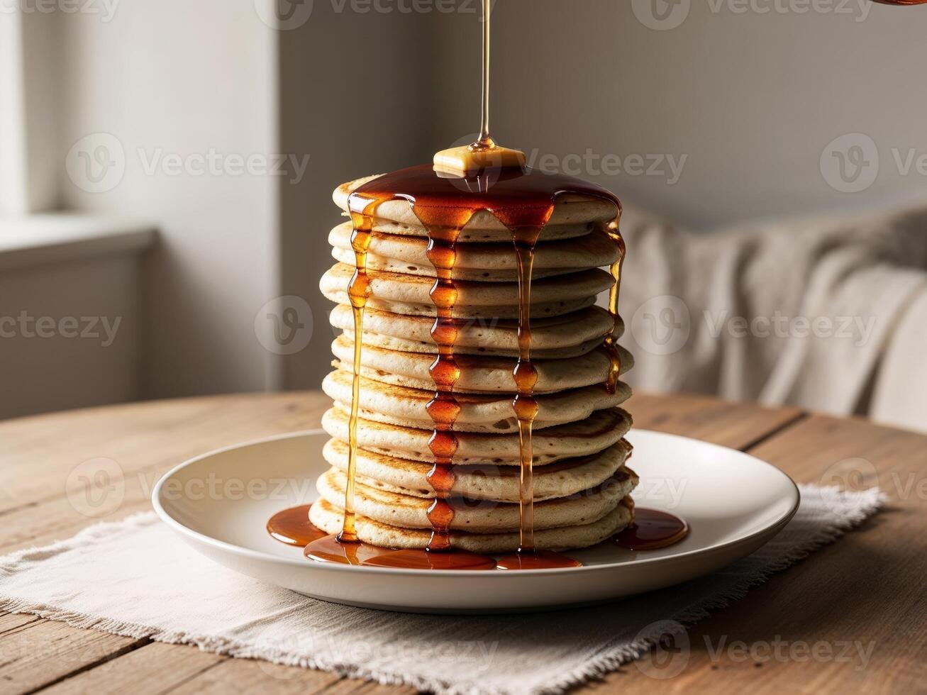 Stack of pancakes with syrup drizzling in warm lighting photo