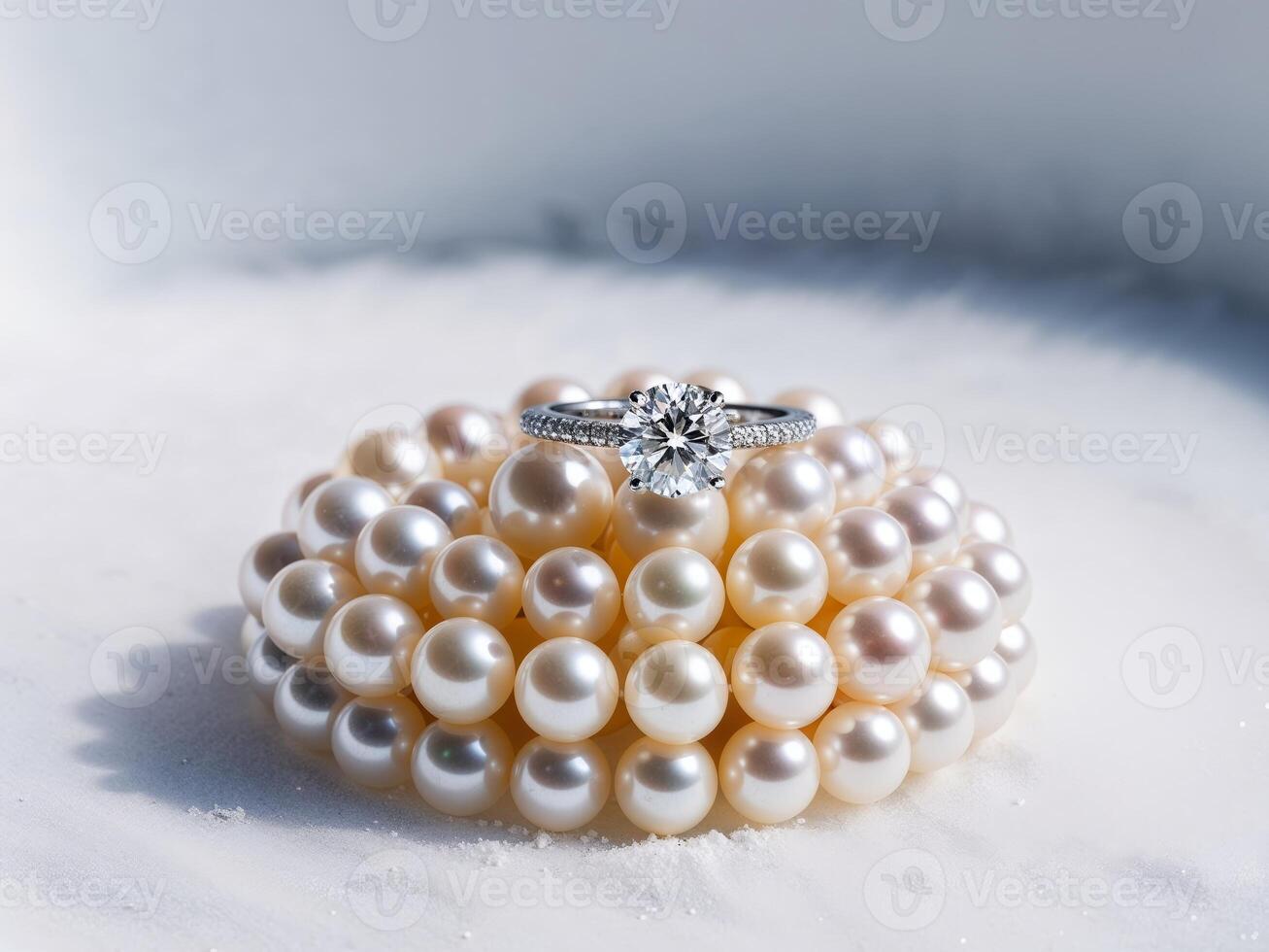 A diamond ring sits atop a pile of lustrous pearls photo