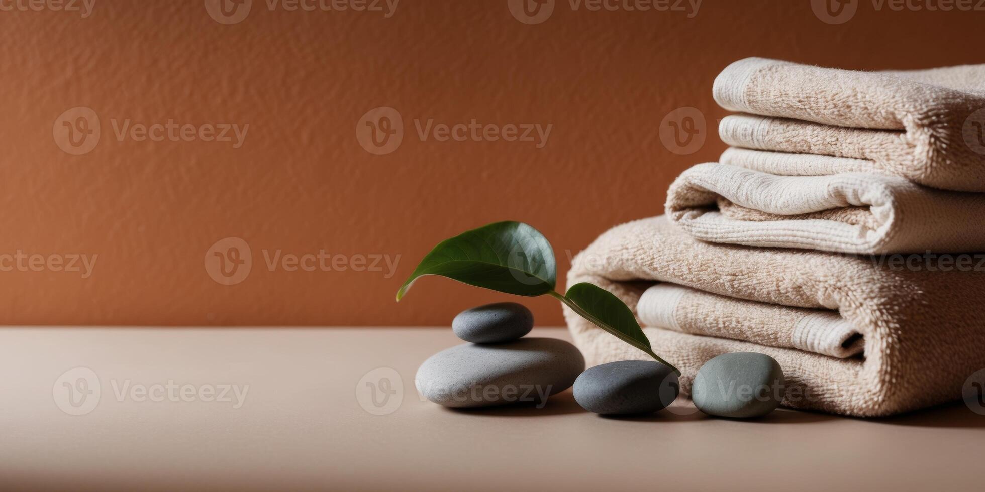 Soft Towels and Smooth Stones with Green Leaf on Orange Wall Background photo