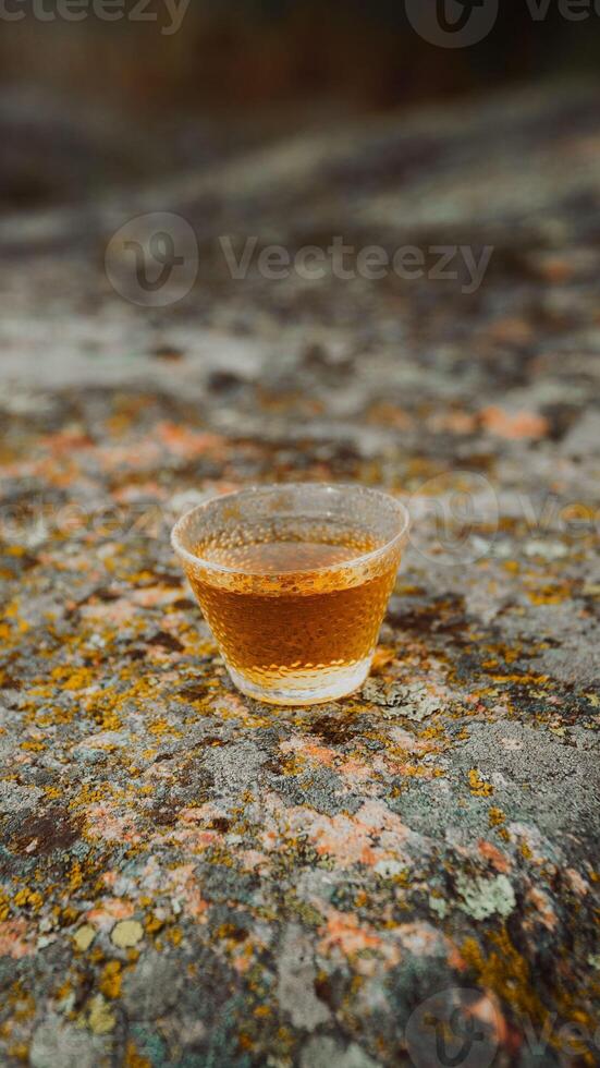 A Glass Filled with a Beautiful Amber Beverage Elegantly Resting on a Textured Rock Surface photo
