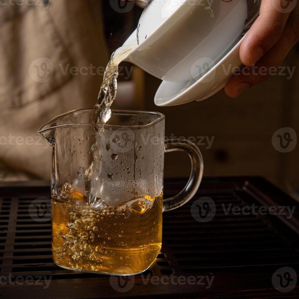 Pouring a flavorful Herbal Tea into a clear Glass Mug while steam rises from it gracefully photo