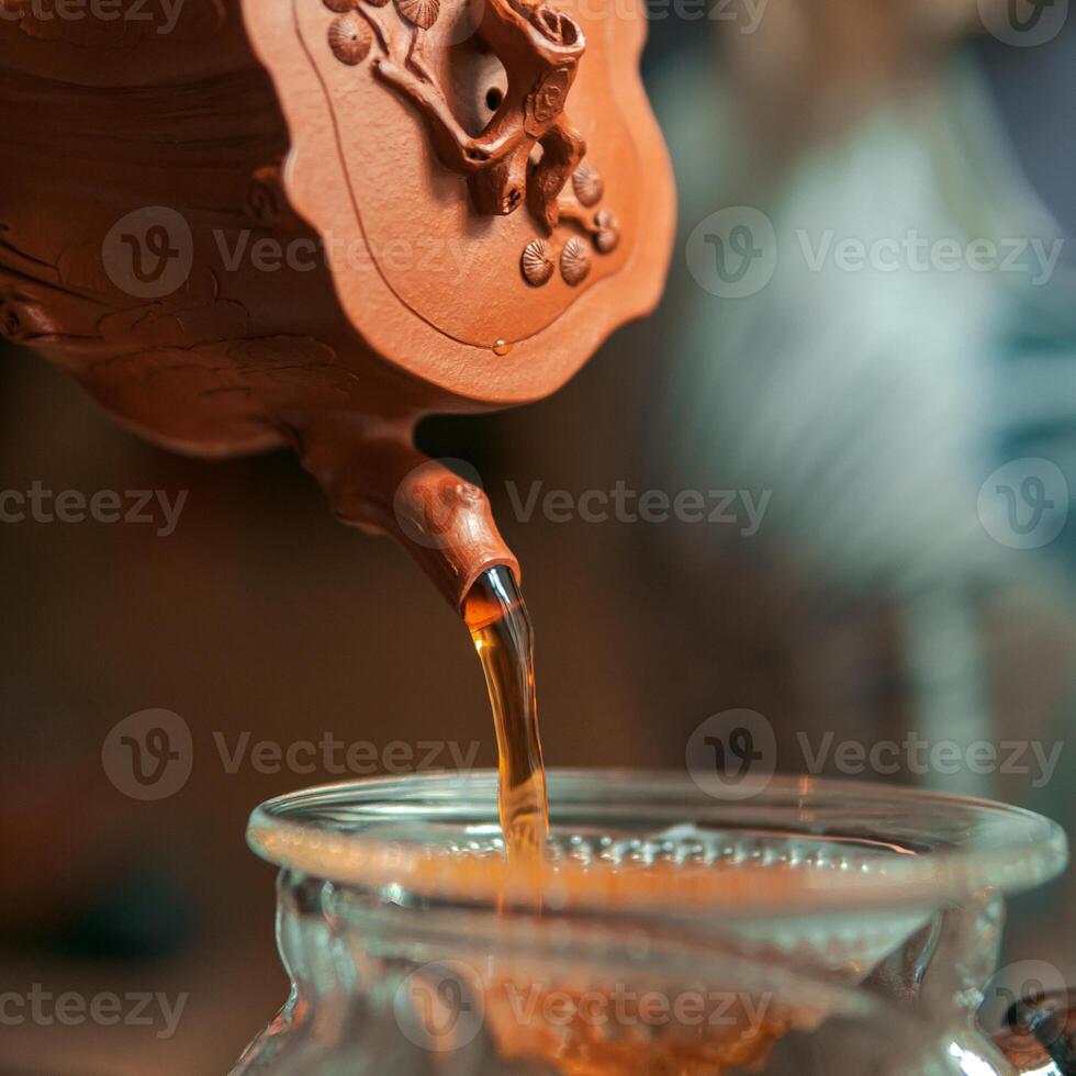 Artisan Tea is Carefully Poured from a Beautiful Traditional Clay Pot for Enjoyment and Relaxation photo