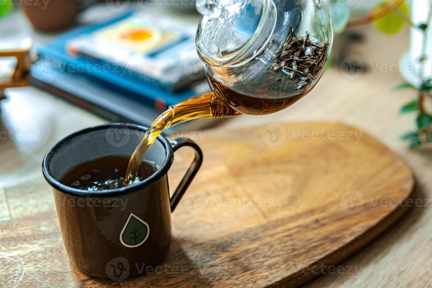 Pouring a delicious cup of tea into a beautiful cup placed on a polished wooden surface photo