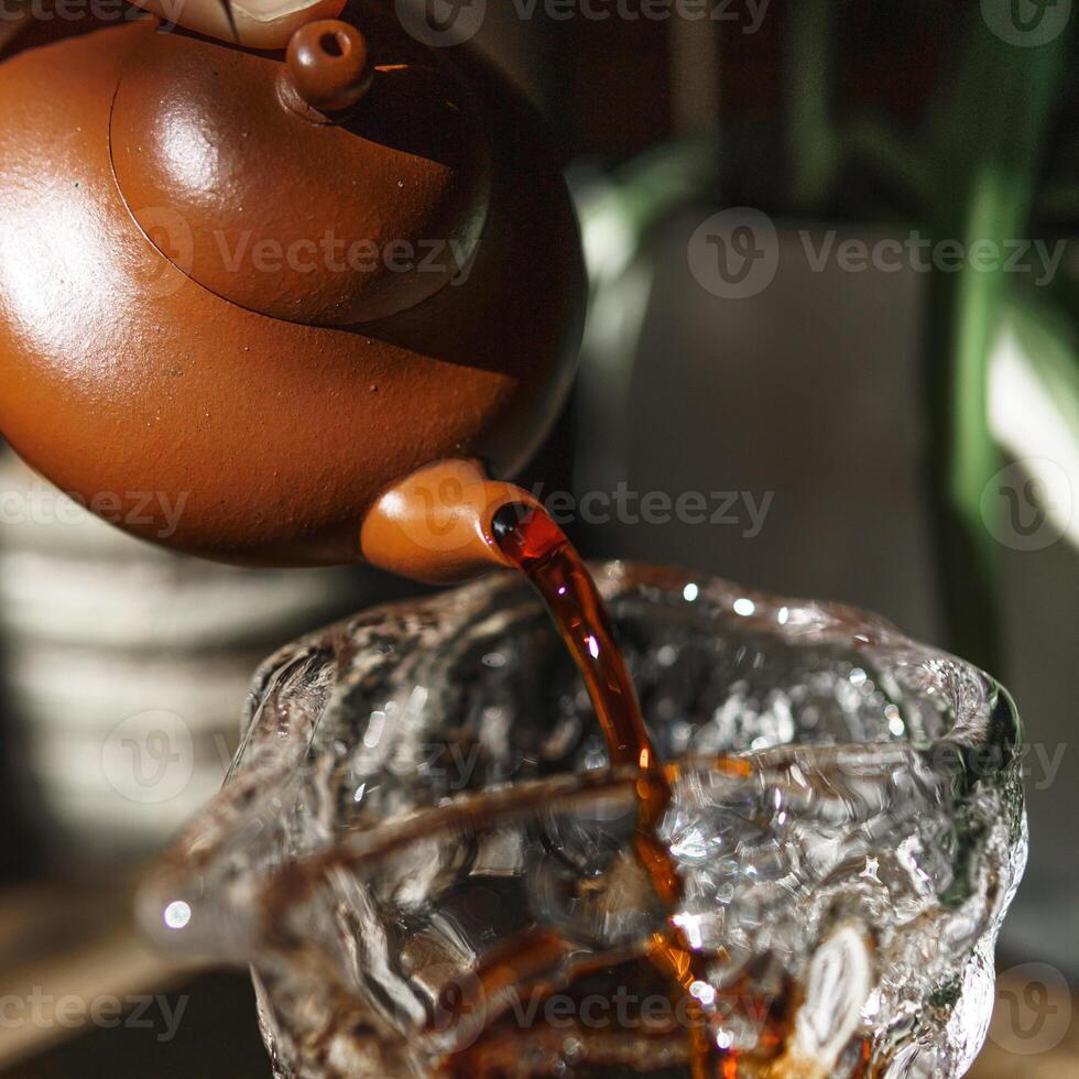 An Elegant Teapot Gently Pouring Aromatic Tea into a Clear Glass, Perfect for Enjoying photo