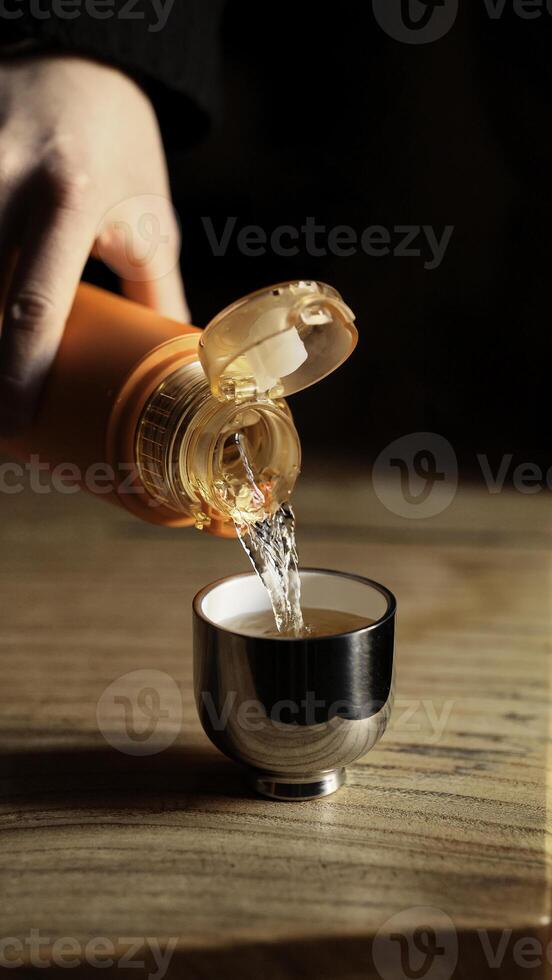 Pouring a Liquid Substance from a Bottle into a Small Shot Glass for Enjoyment or Celebration photo