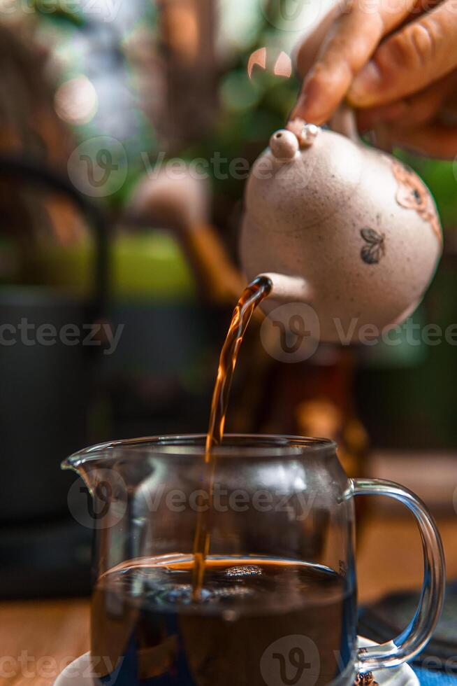 Traditional Teapot Pouring Tea into a Beautiful Glass Teacup for an Enjoyable Experience photo