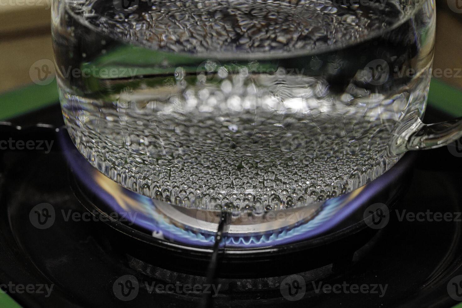 Water is boiling on the stove with bubbles steadily rising from the heated liquid surface photo