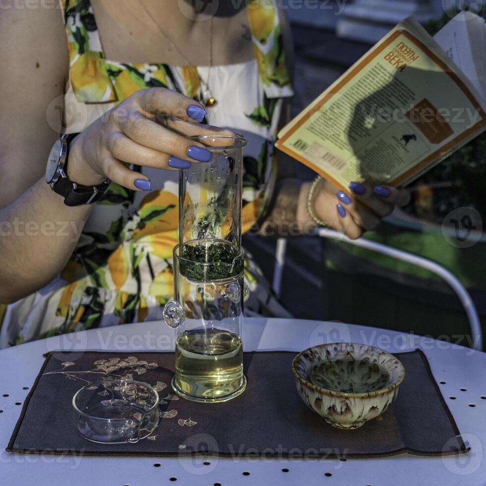 Embracing a Refreshing Herbal Tea Ritual While Surrounded by a Book and a Floral Background photo